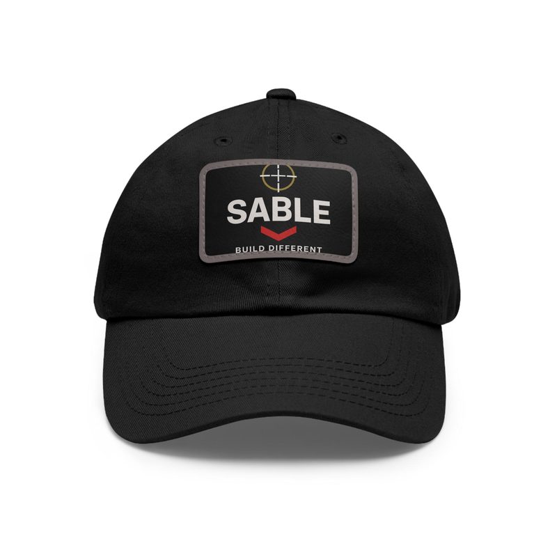 The SABLE black cap by BySable, photographed on a plain background, with a rubber patch reading SABLE, a red chevron, and the words Build Different.